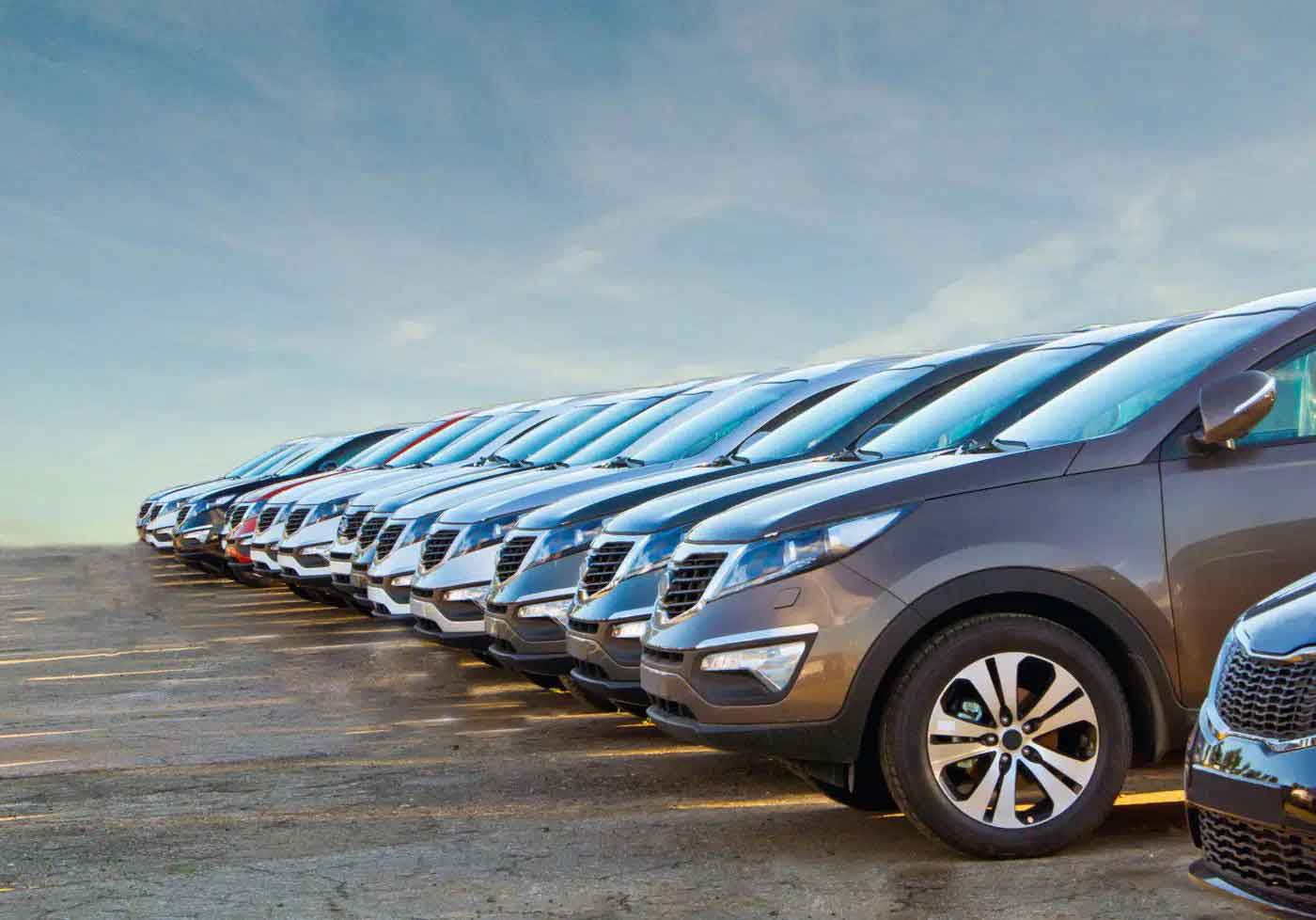 Row of parked new SUVs lined up in a dealership lot under a clear sky