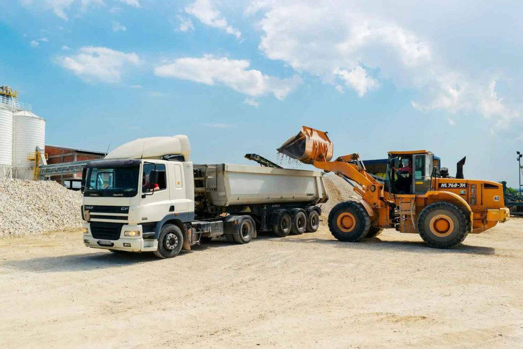 Excavator loading gravel into a dump truck at a construction site
